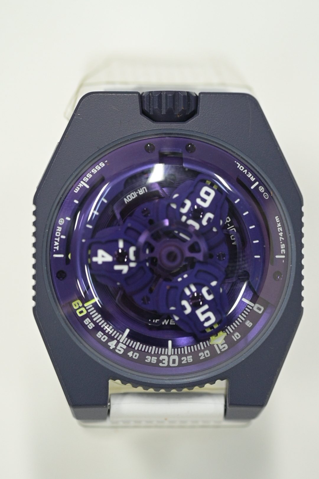 URWERK UR-100V with satellite hour carousel over a purple baseplate, on a translucent white rubber strap
